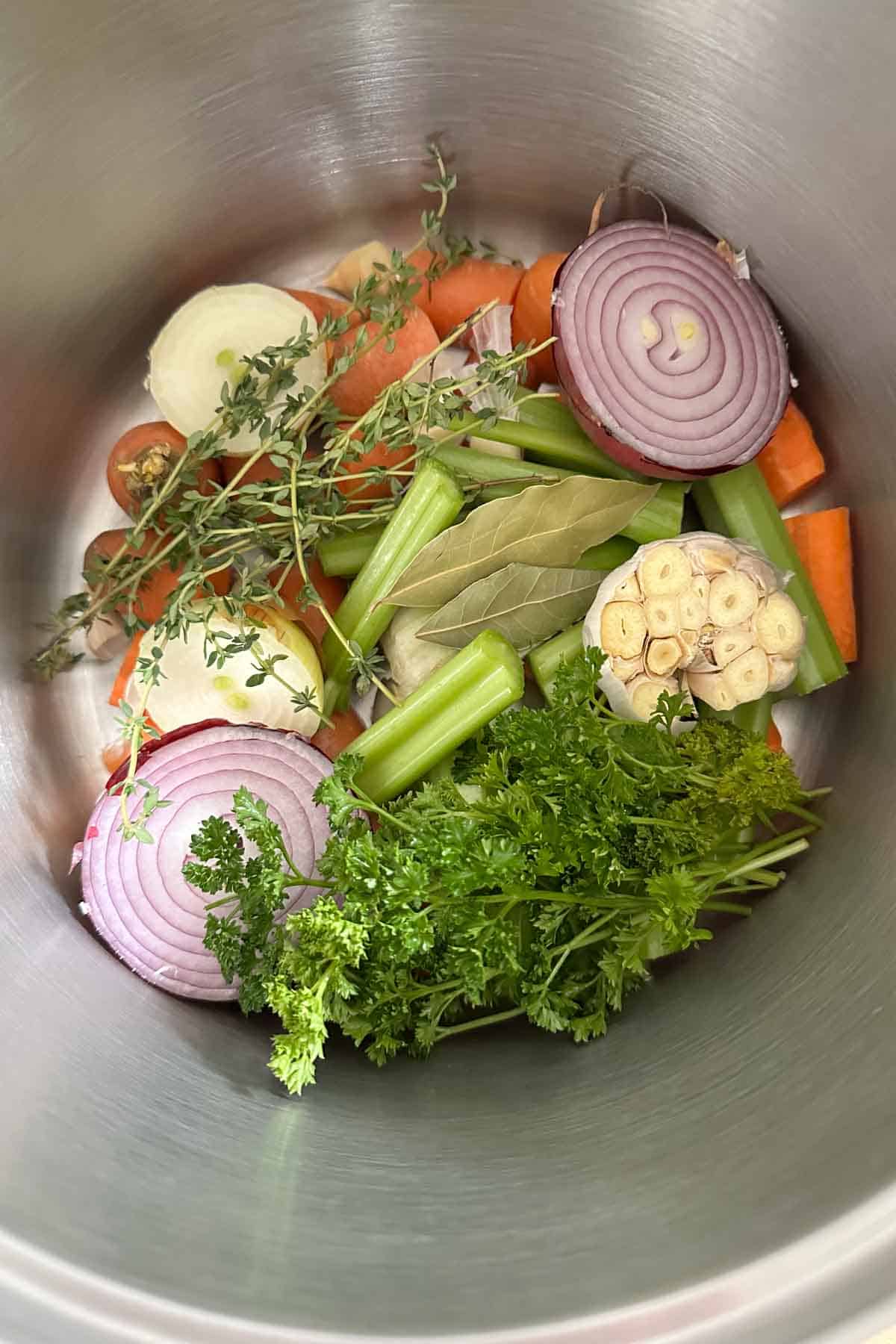 Pot filled with vegetables and herbs to make homemade vegetable stock.
