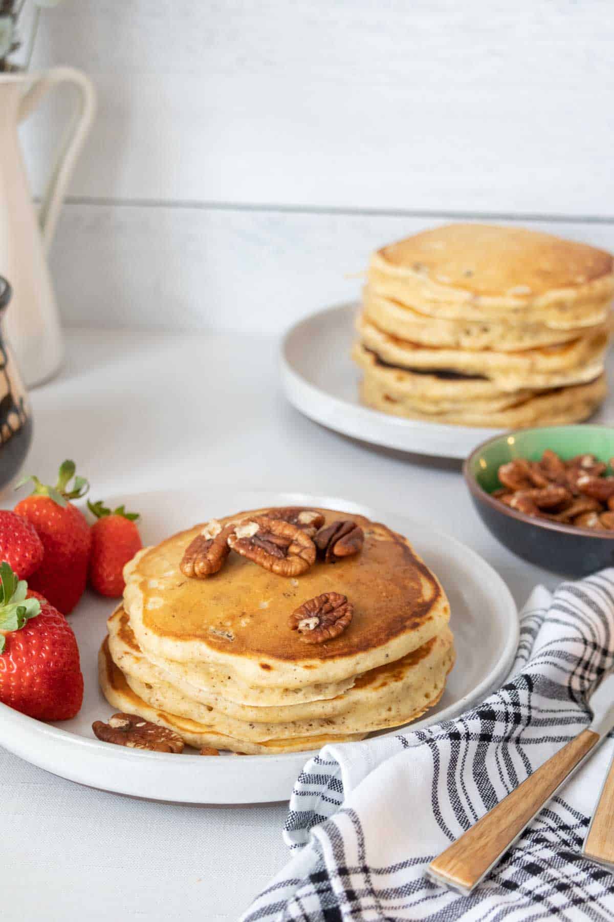 Plate of pecan pancakes with another plate of pancakes behind.