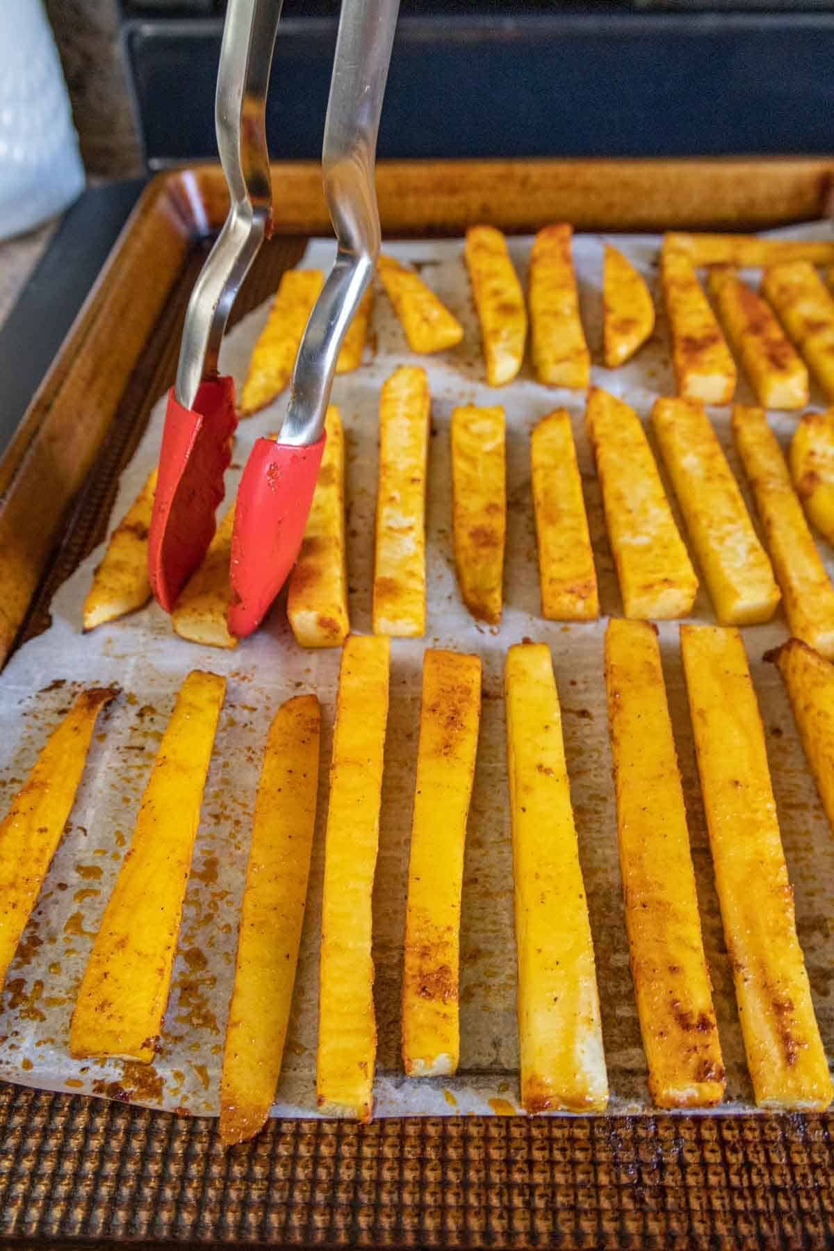 Flipping rutabaga fries using tongs.