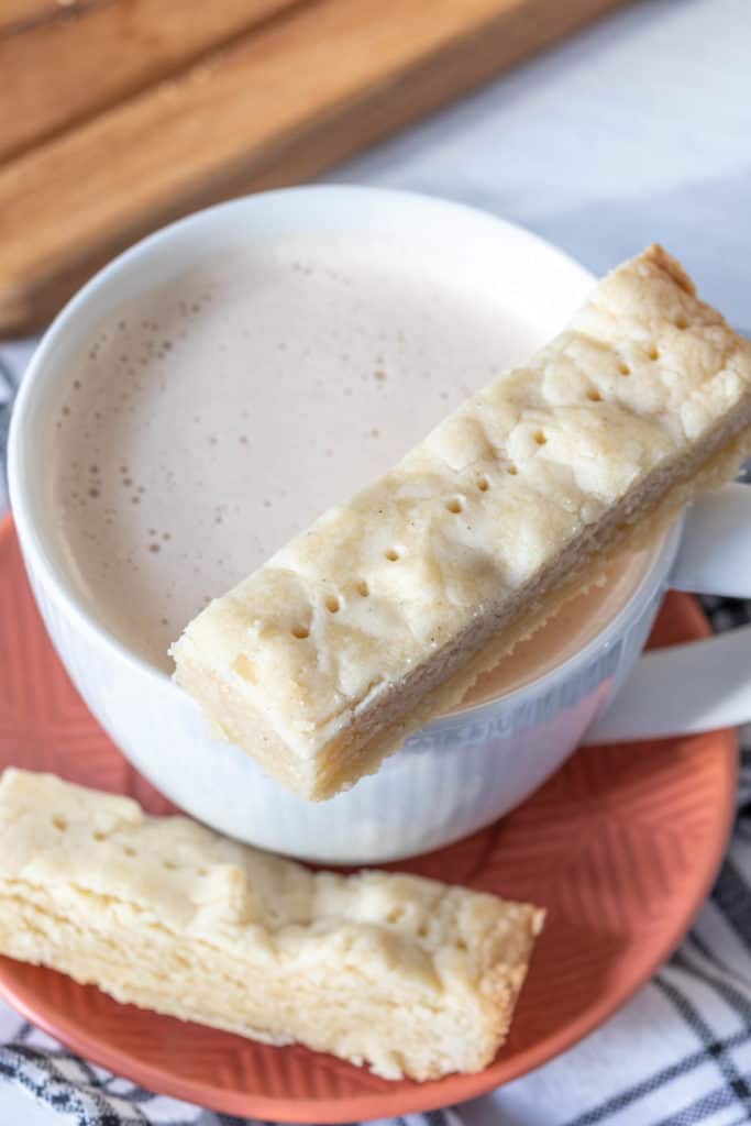 Sliced shortbread cookie resting on a cup of chai.