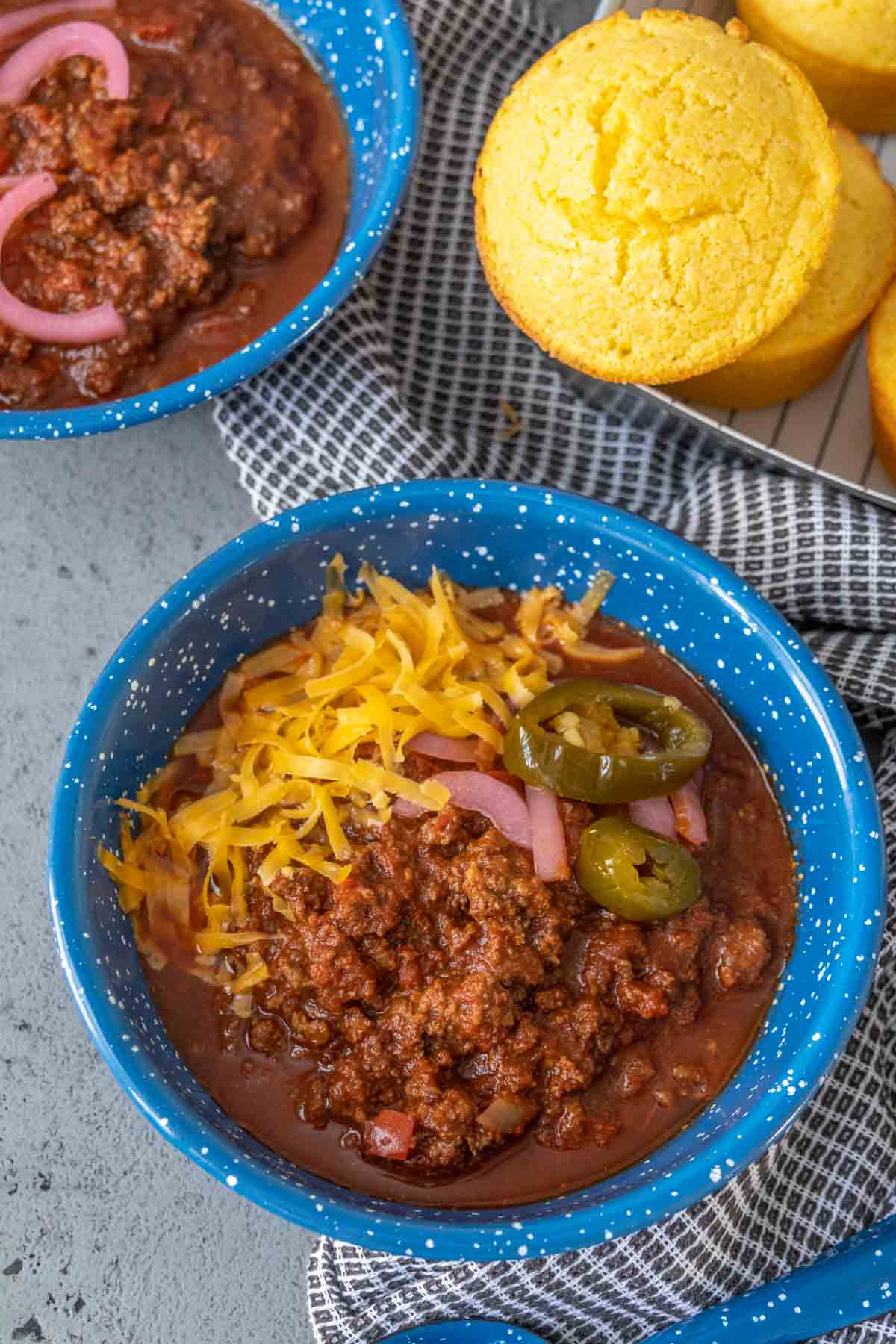 Bowl of bison chili with shredded cheese and jalapeños on top.