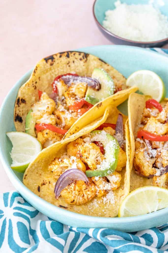 Plate of cauliflower tacos with toppings on a blue plate.