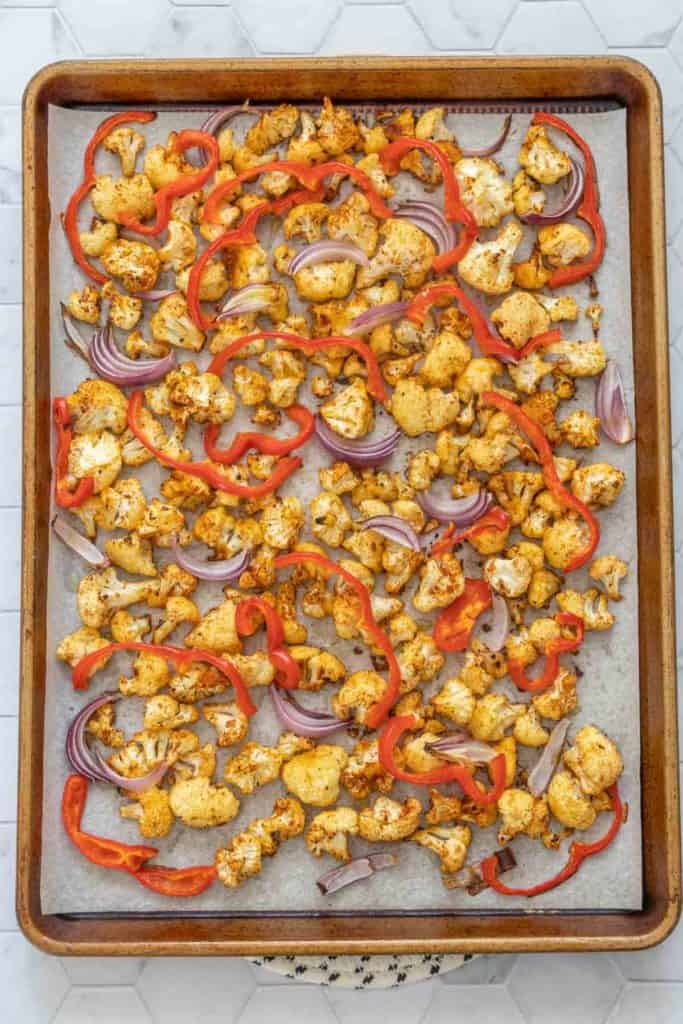 Roasted cauliflower, onion, and bell pepper on a baking sheet.