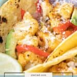 Close-up of delicious cauliflower tacos featuring roasted cauliflower, red bell peppers, avocado slices, cotija cheese, and a lime wedge in a warm corn tortilla.