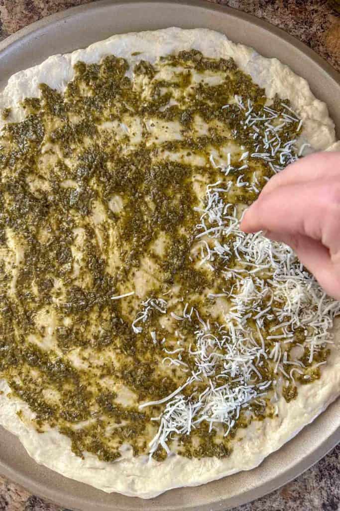 Adding cheese to unbaked pizza.