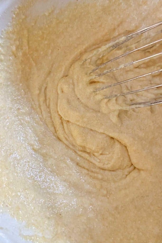 Mixed corn muffin batter in a bowl with a whisk.
