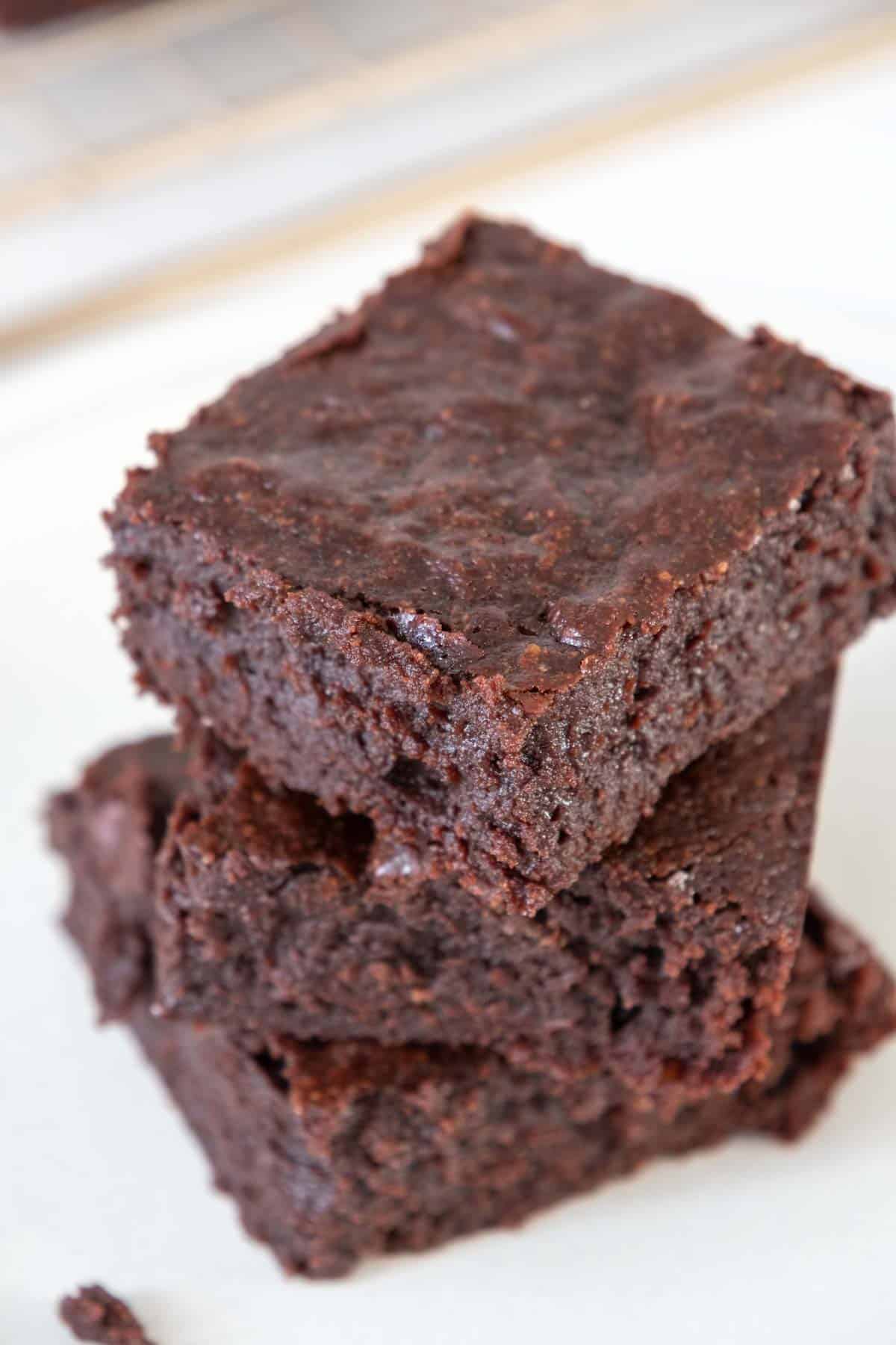 Stacked fudgy brownies on a white plate.