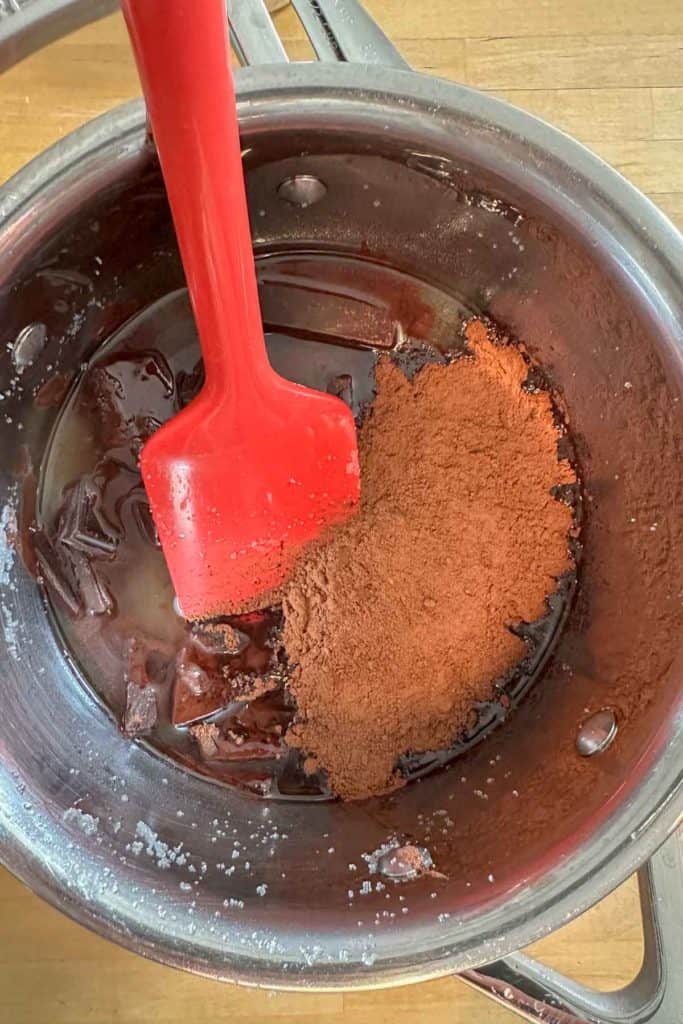 Melting chocolate and cocoa powder in warmed sugar for brownies.