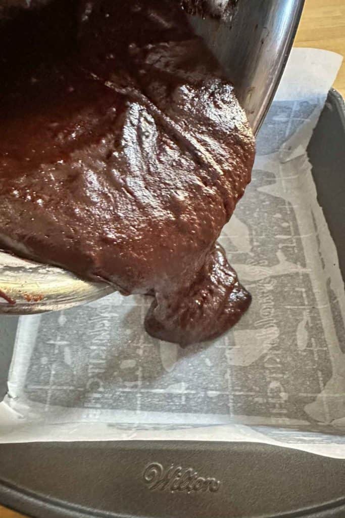 Pouring brownie batter into a baking pan.