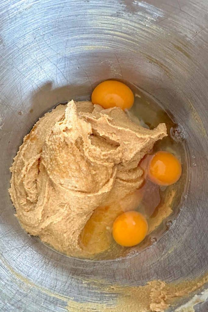 Eggs and vanilla being mixed into creamed butter and sugar.