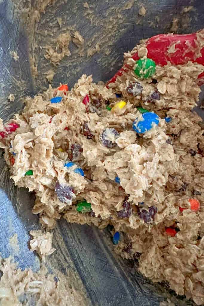 Monster cookie dough in mixing bowl with red spatula.