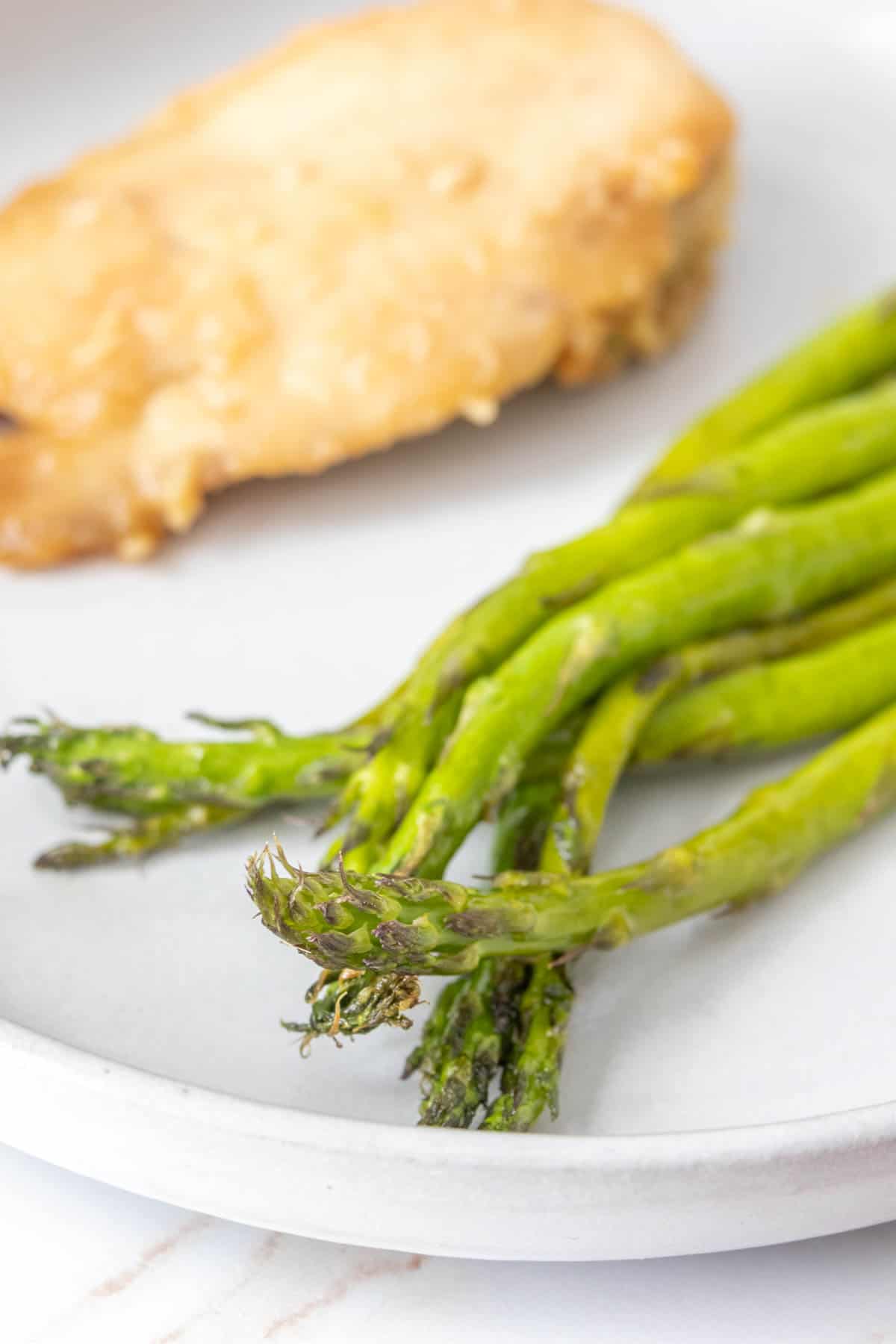 Close up of roasted asparagus spears on a plate.