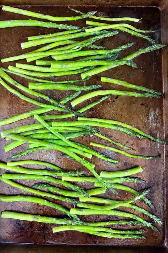 Roasted asparagus on an aged baking sheet.