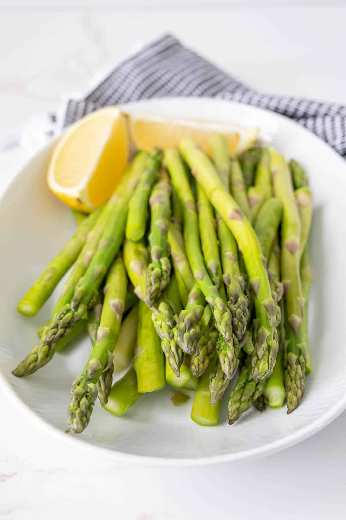 Platter of steamed asparagus with lemon slices.