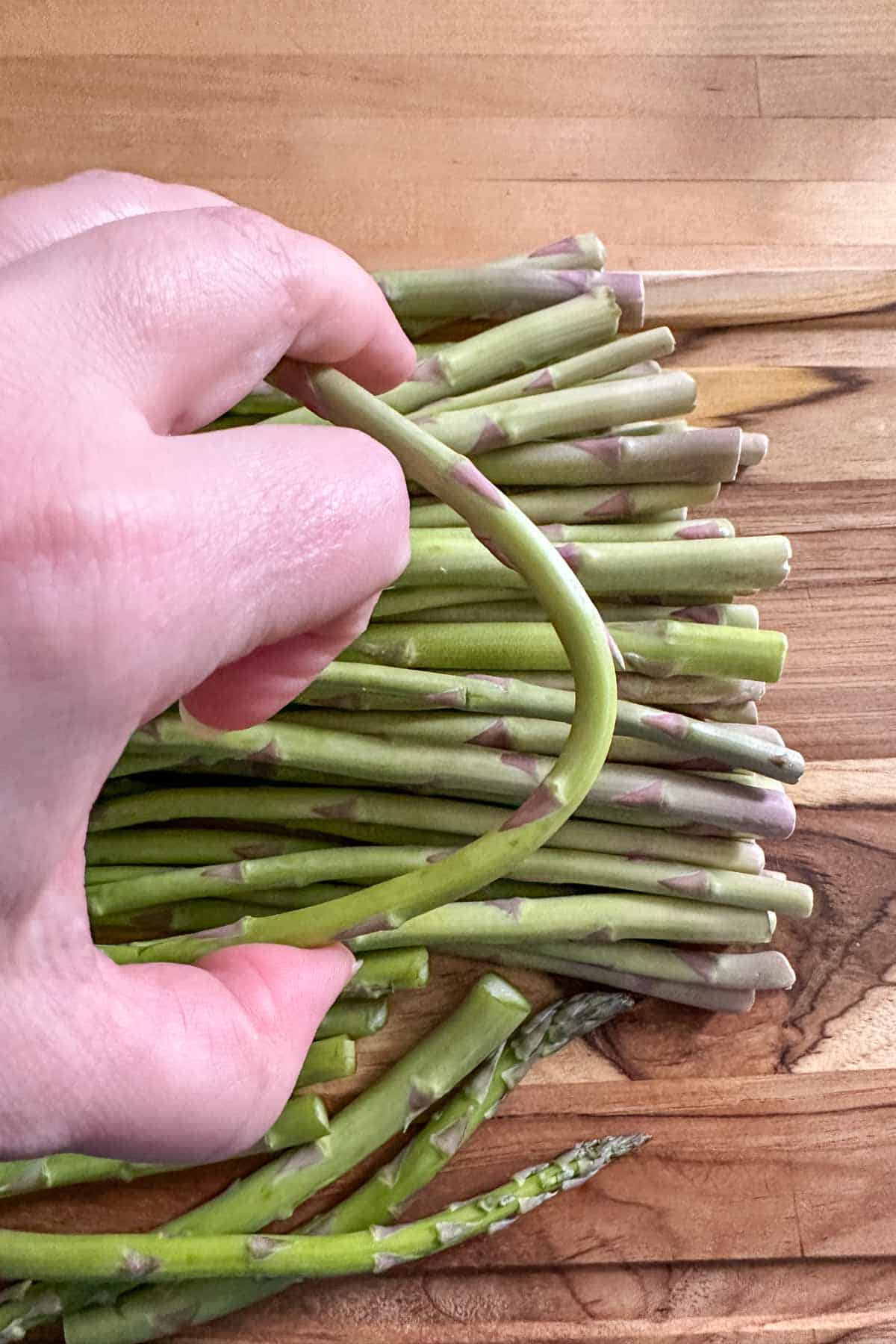Breaking woody ends off asparagus.
