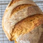 Loaf of baked limpa bread cooling on a wire rack.