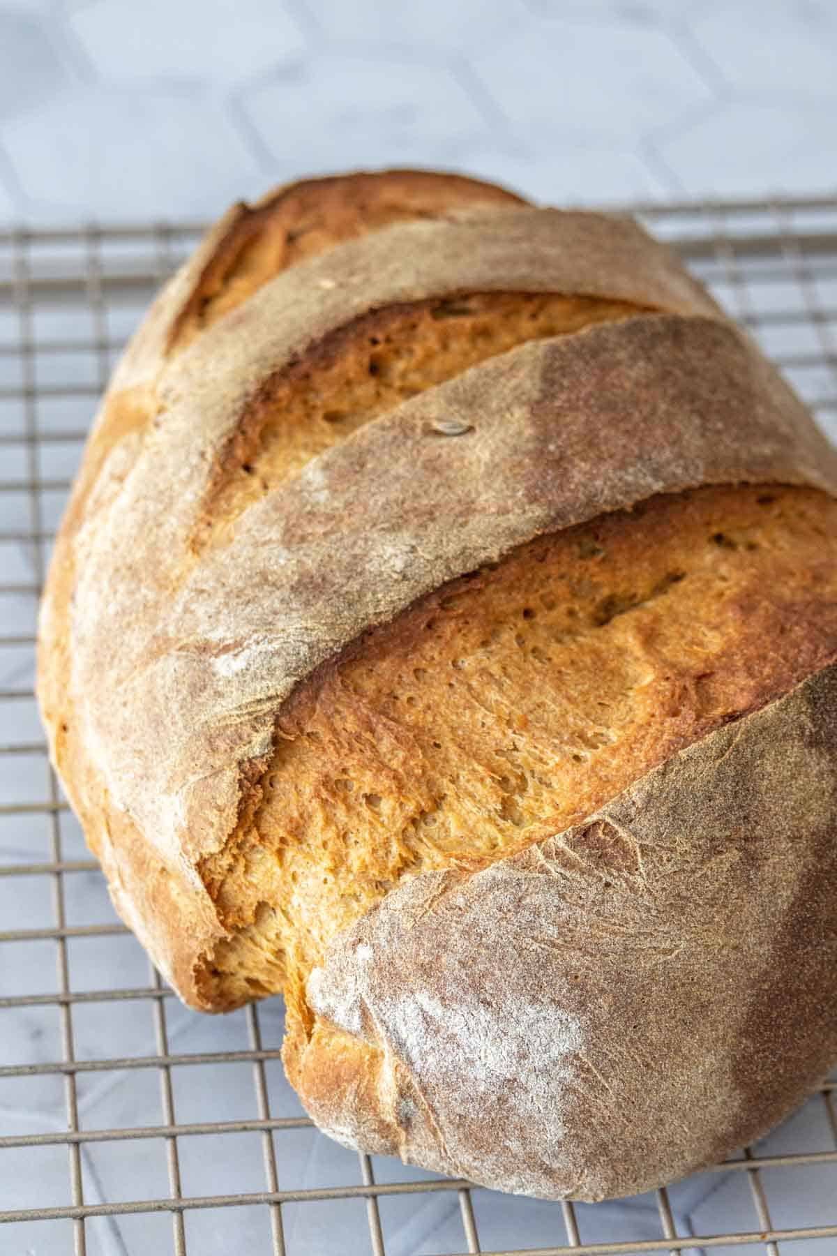 Loaf of baked limpa bread cooling on a wire rack.