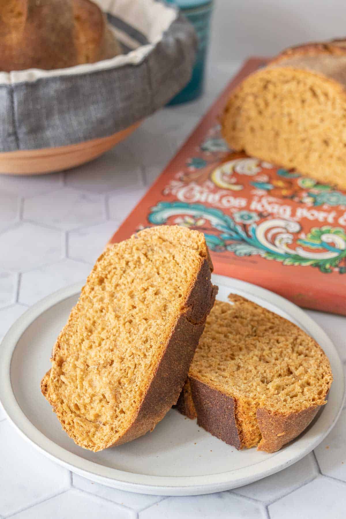 Two slices of limpa bread on a gray plate with rest of loaf on a bread board behind.