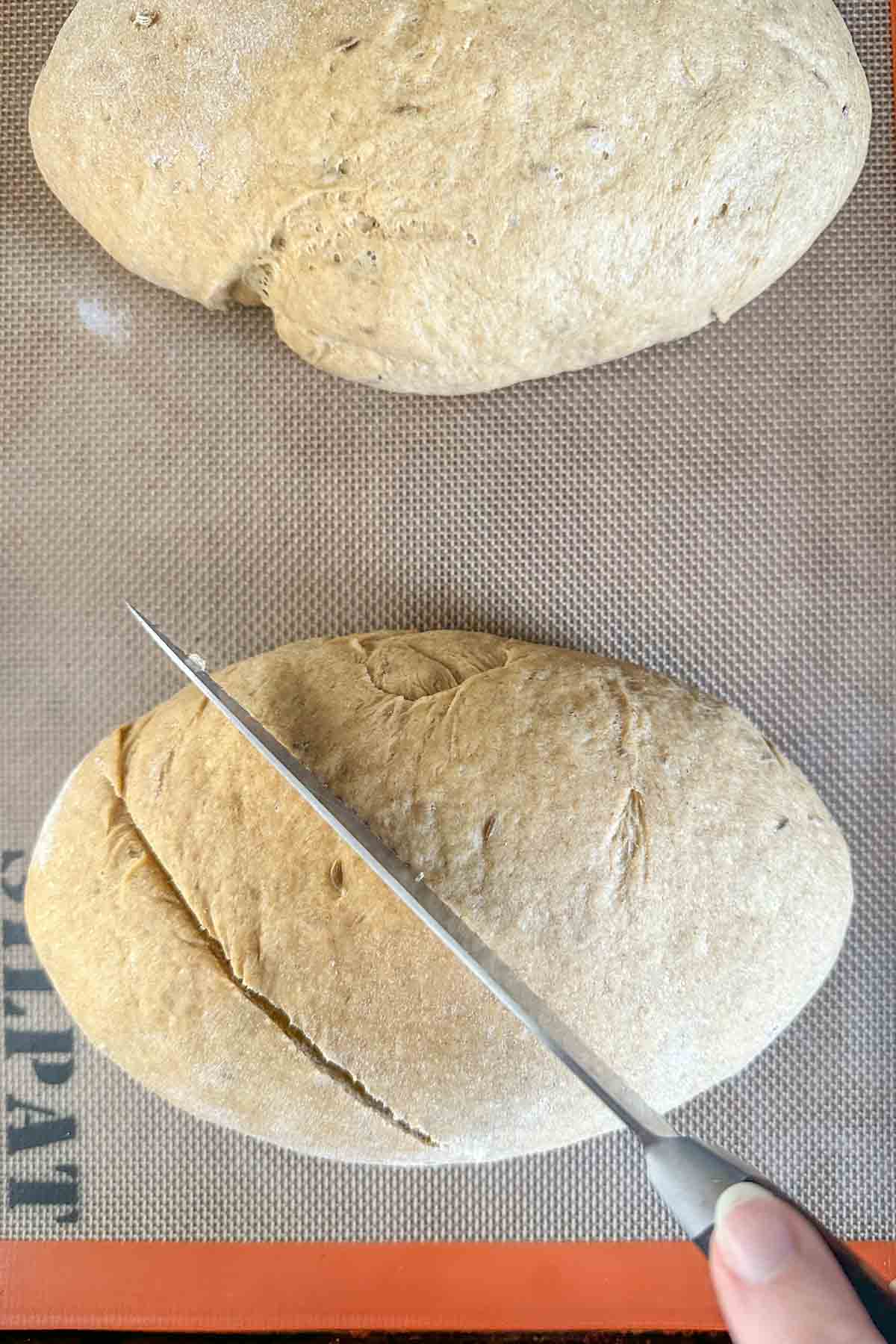 Slashing limpa bread loaves before baking.