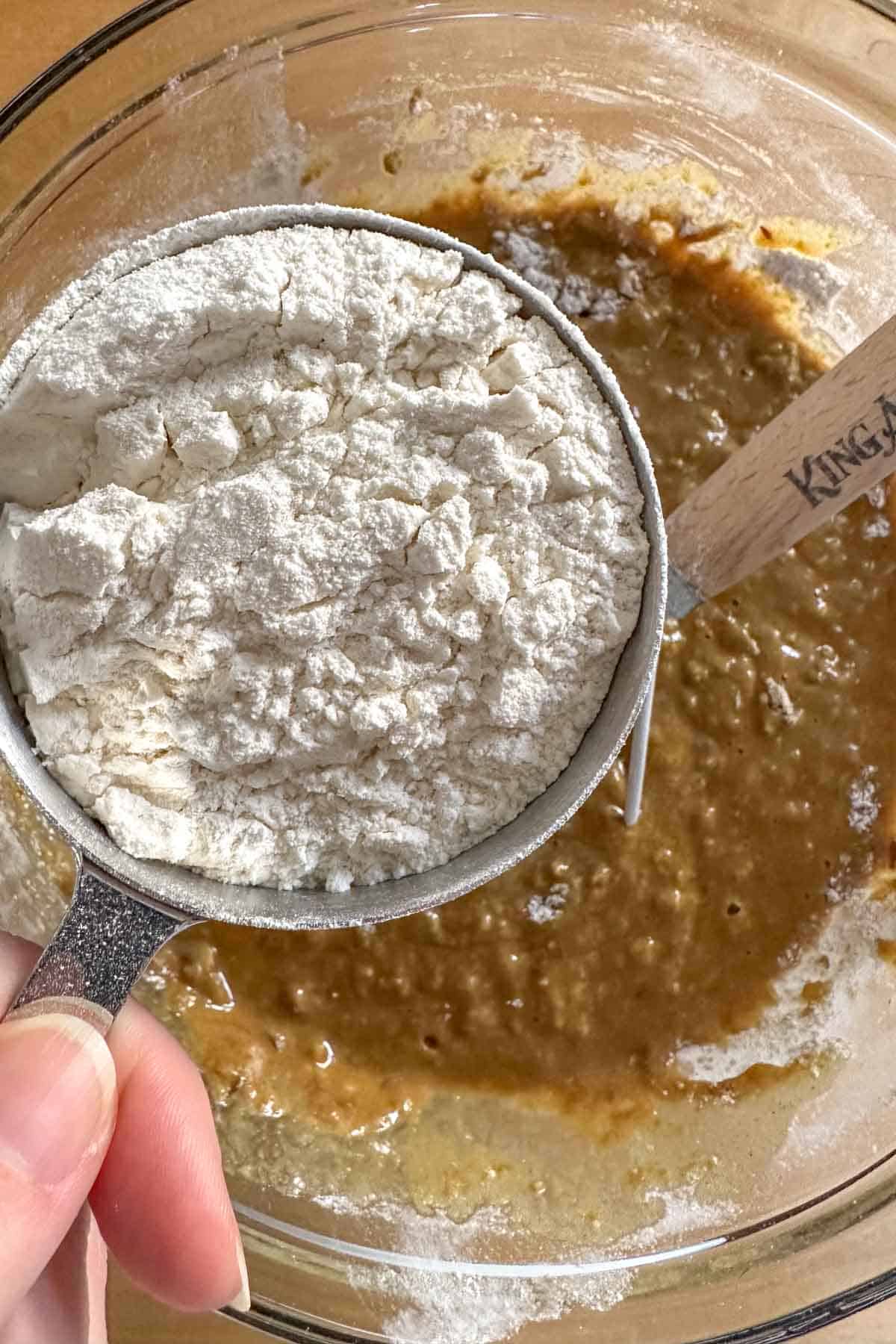 Adding flour to bread dough in mixing bowl.