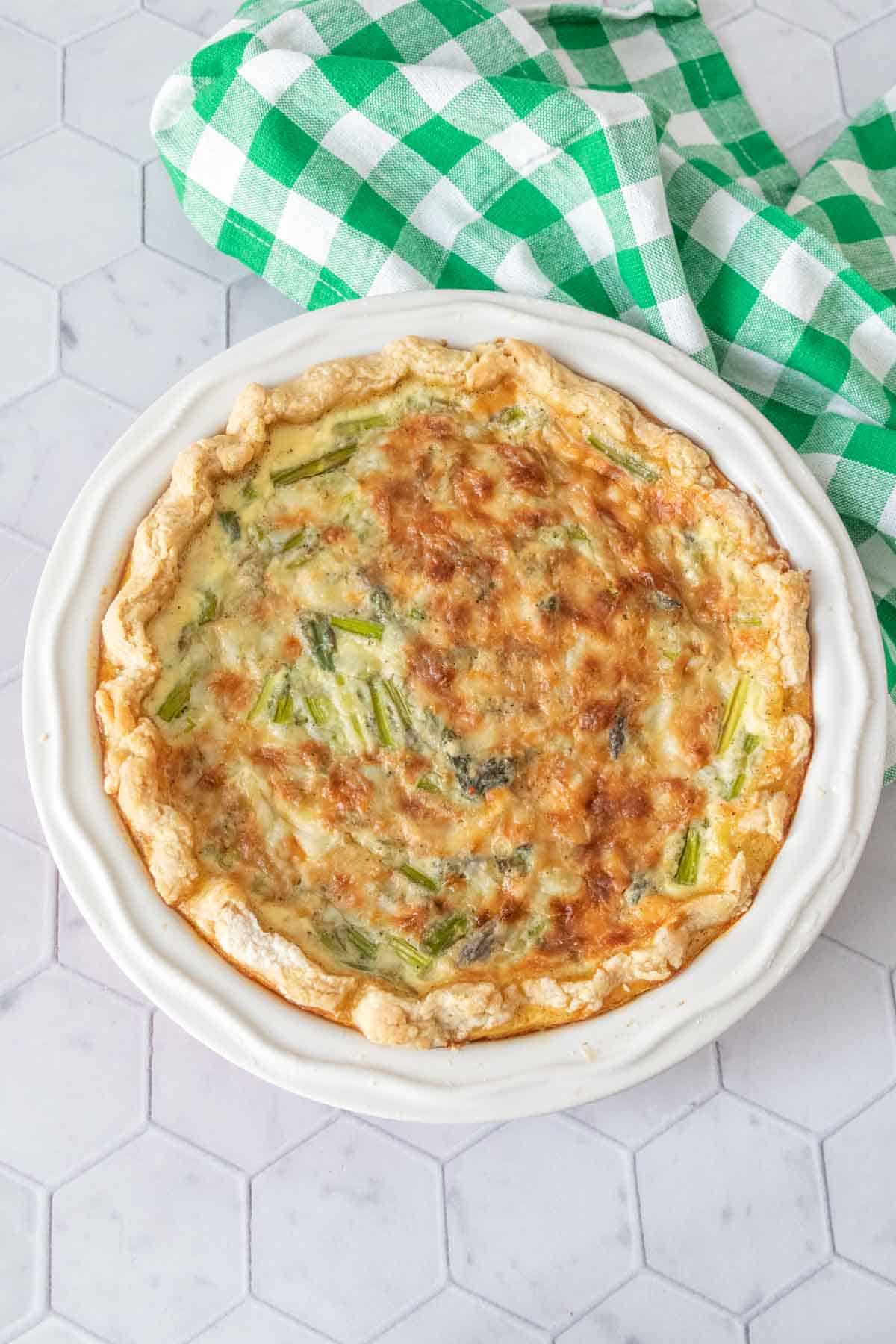 Baked asparagus quiche with a green patterned napkin beside.