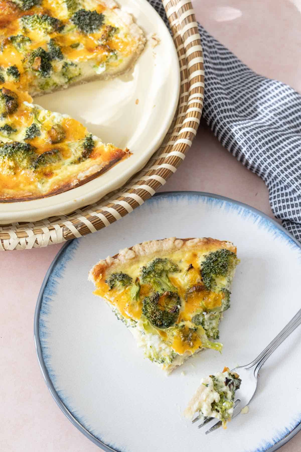 Slice of broccoli cheddar quiche with a piece on a fork.