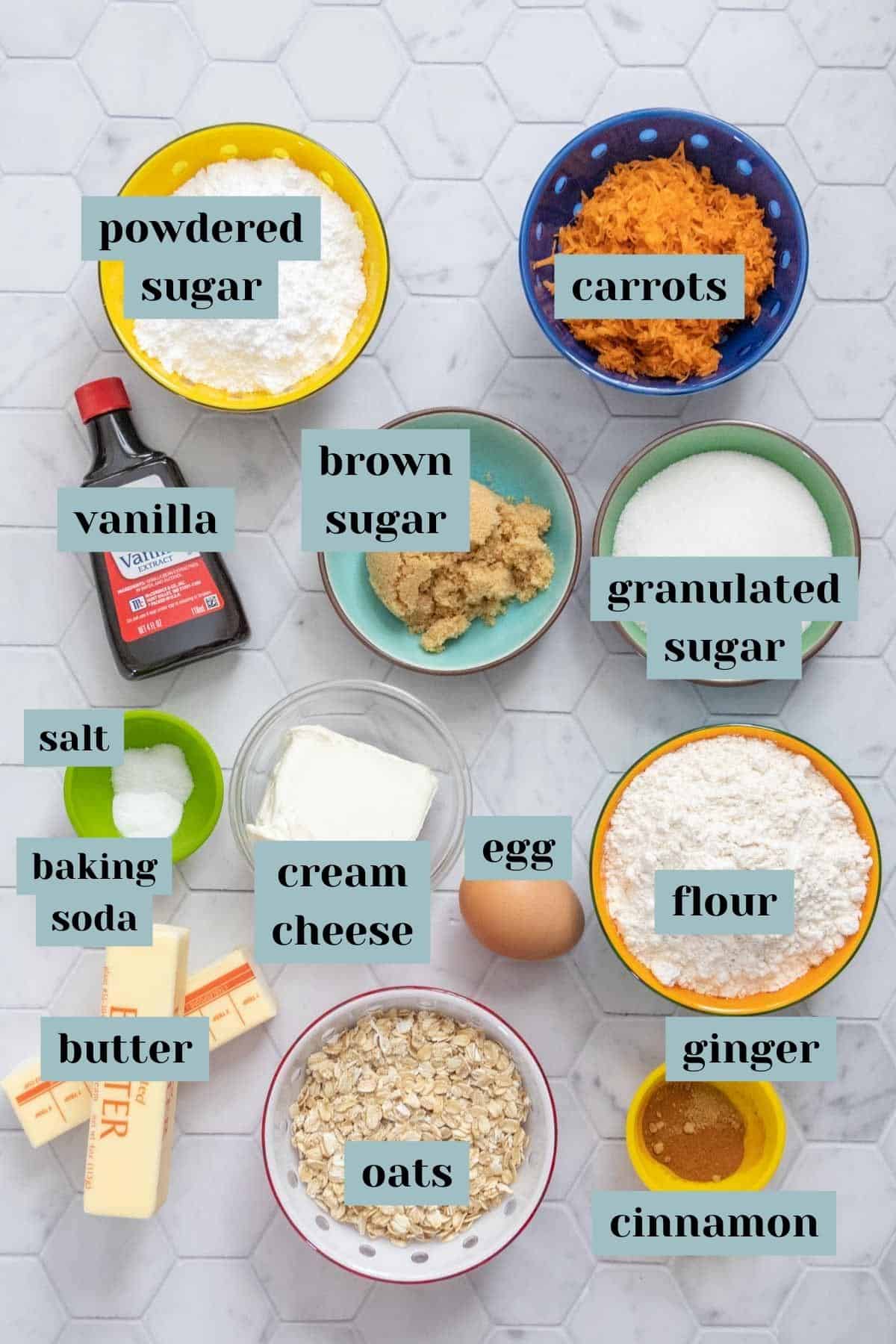 Ingredients for carrot cake cookies on a tile surface labeled.