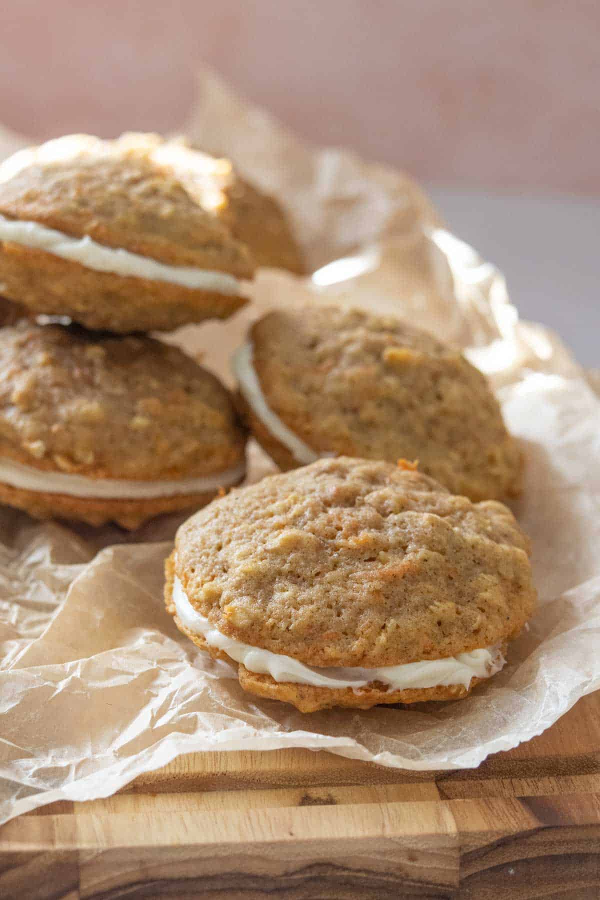 Carrot cake cookies with cream cheese frosting on a sheet of parchment paper.