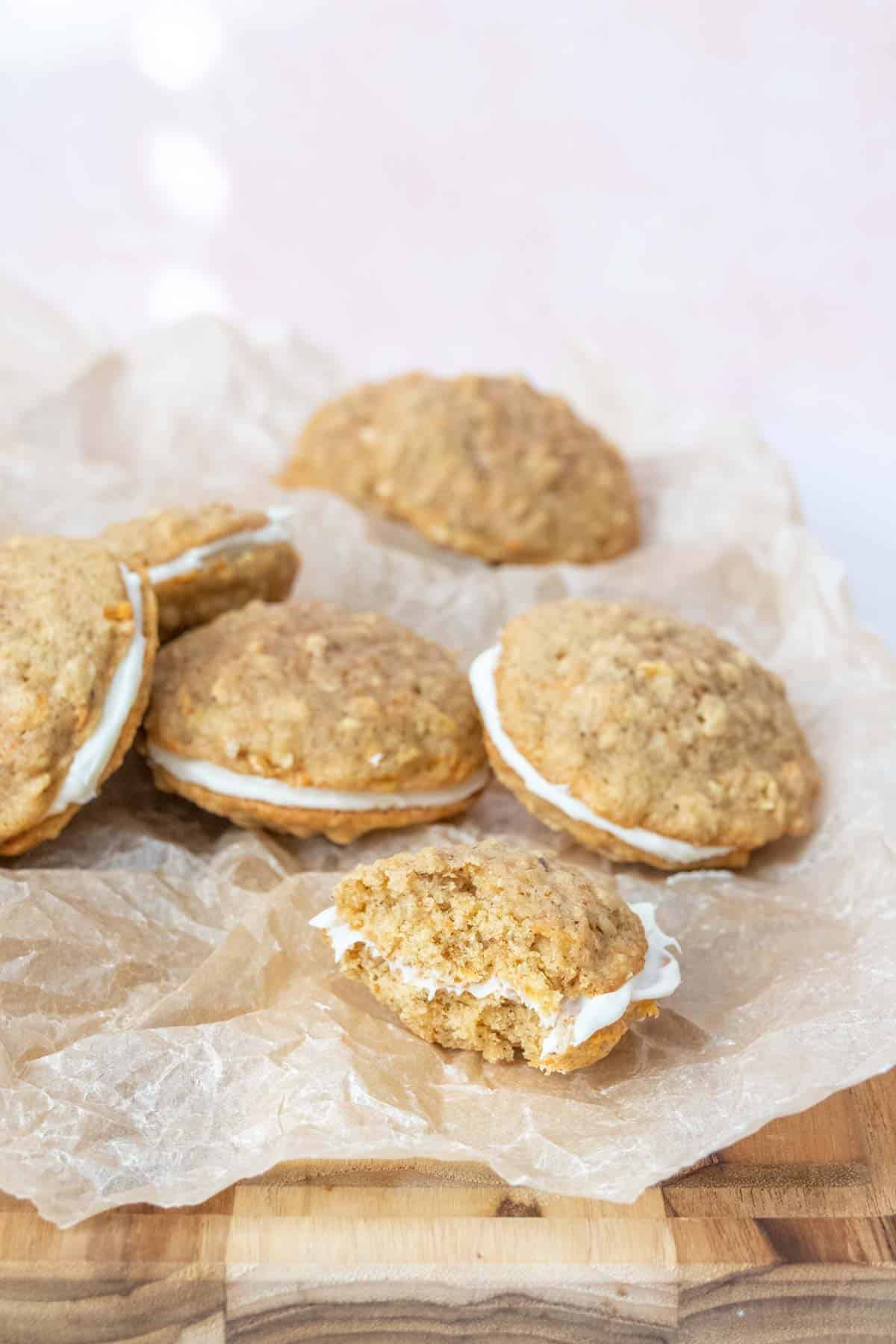 Pile of carrot cake cookies with one partially eaten in front.