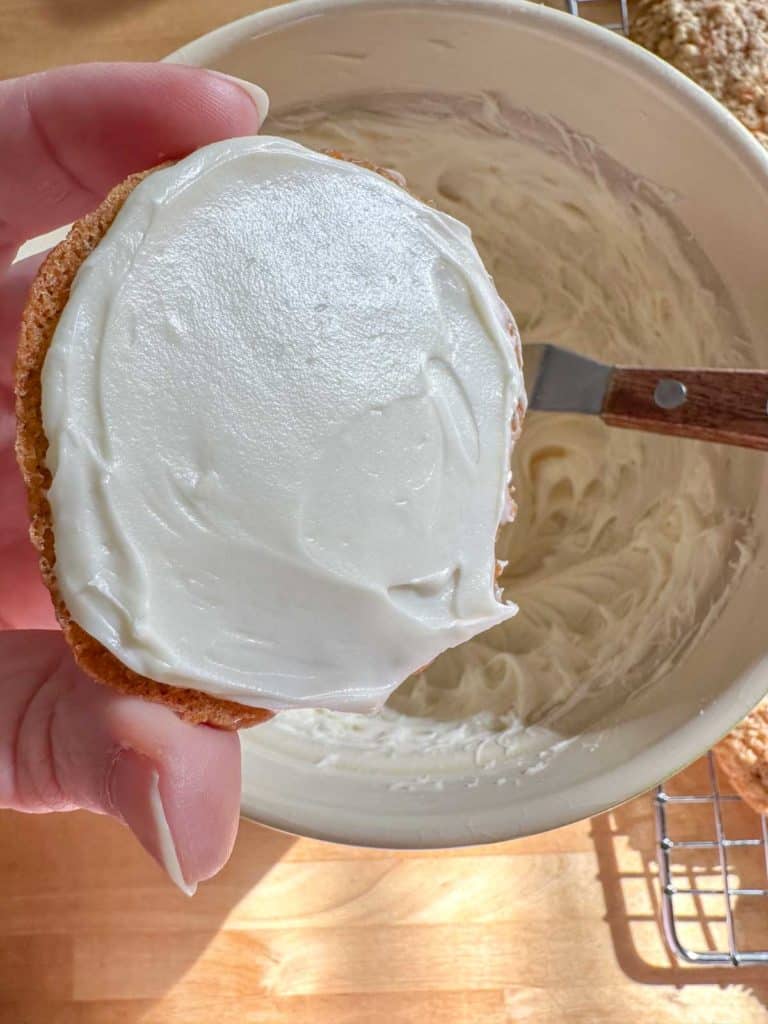 Frosting on one half of carrot cake sandwich cookies.