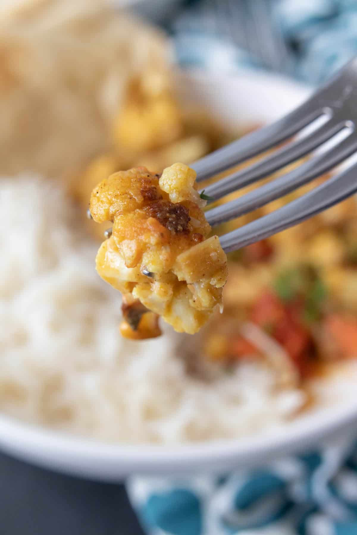 Closeup of cauliflower curry on a fork.