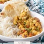 A plate of cauliflower curry served with white rice and naan bread, garnished with chopped herbs for a flavorful vegetarian meal.
