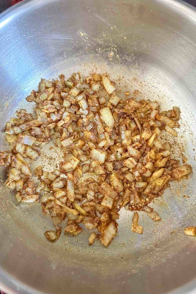 Onions sauteed with spices in pan.