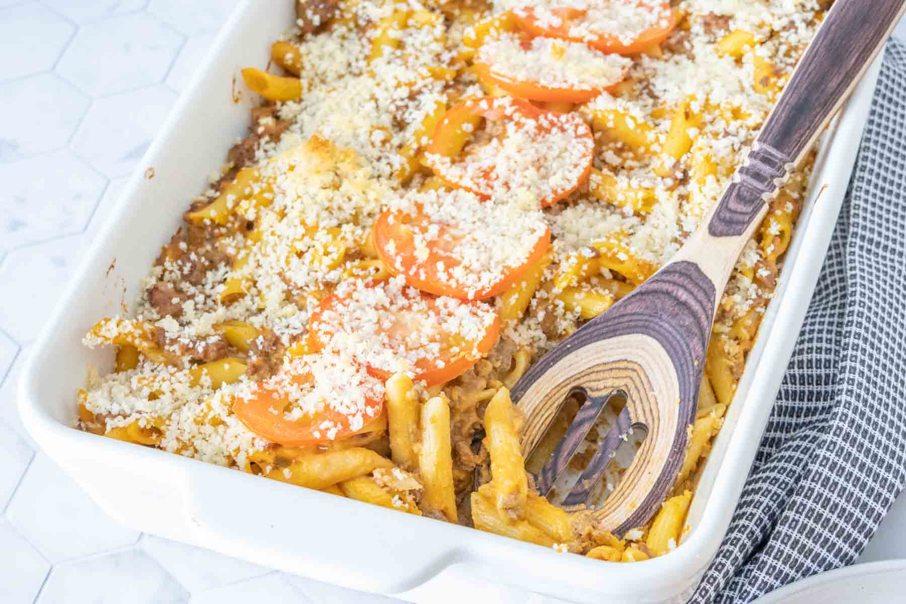 Casserole dish of cheeseburger mac and cheese with wooden spoon.