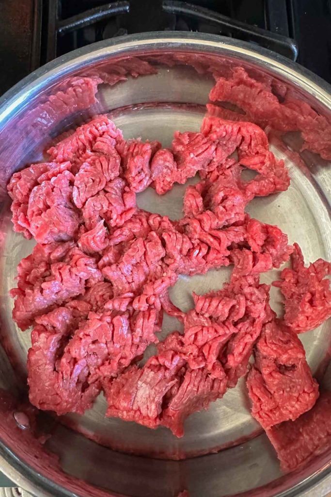 Raw ground beef in skillet for browning.