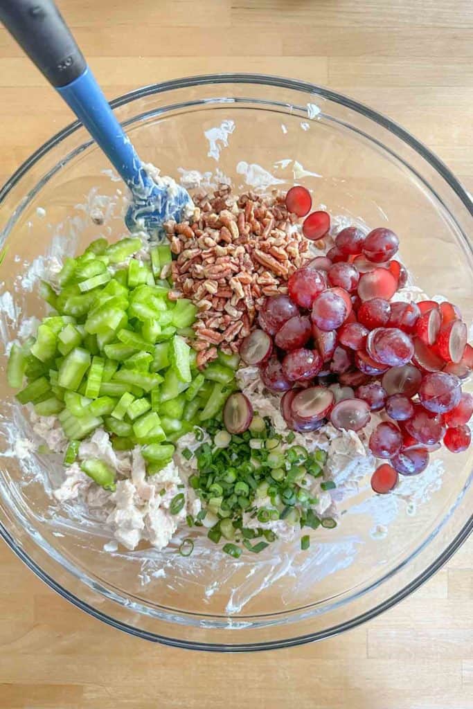 Glass mixing bowl with ingredients for chicken salad.