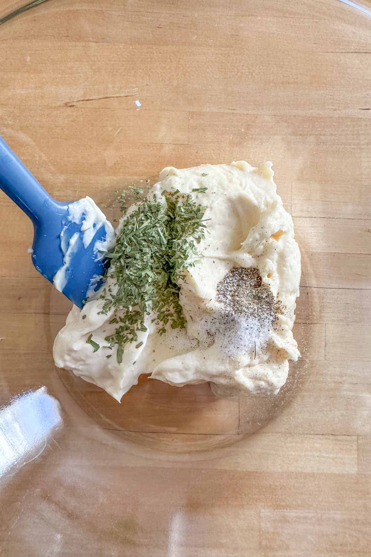 Mayonnaise, tarragon, salt, and pepper in a glass mixing bowl.