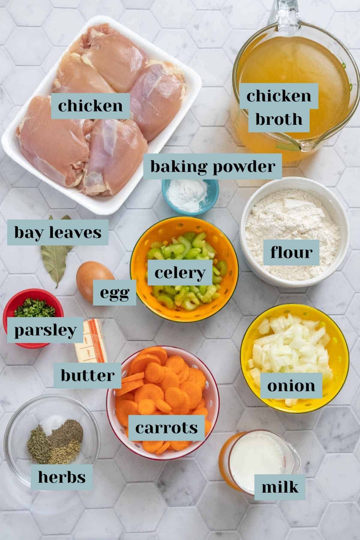 Ingredients for chicken and dumplings on a tile surface with labels.