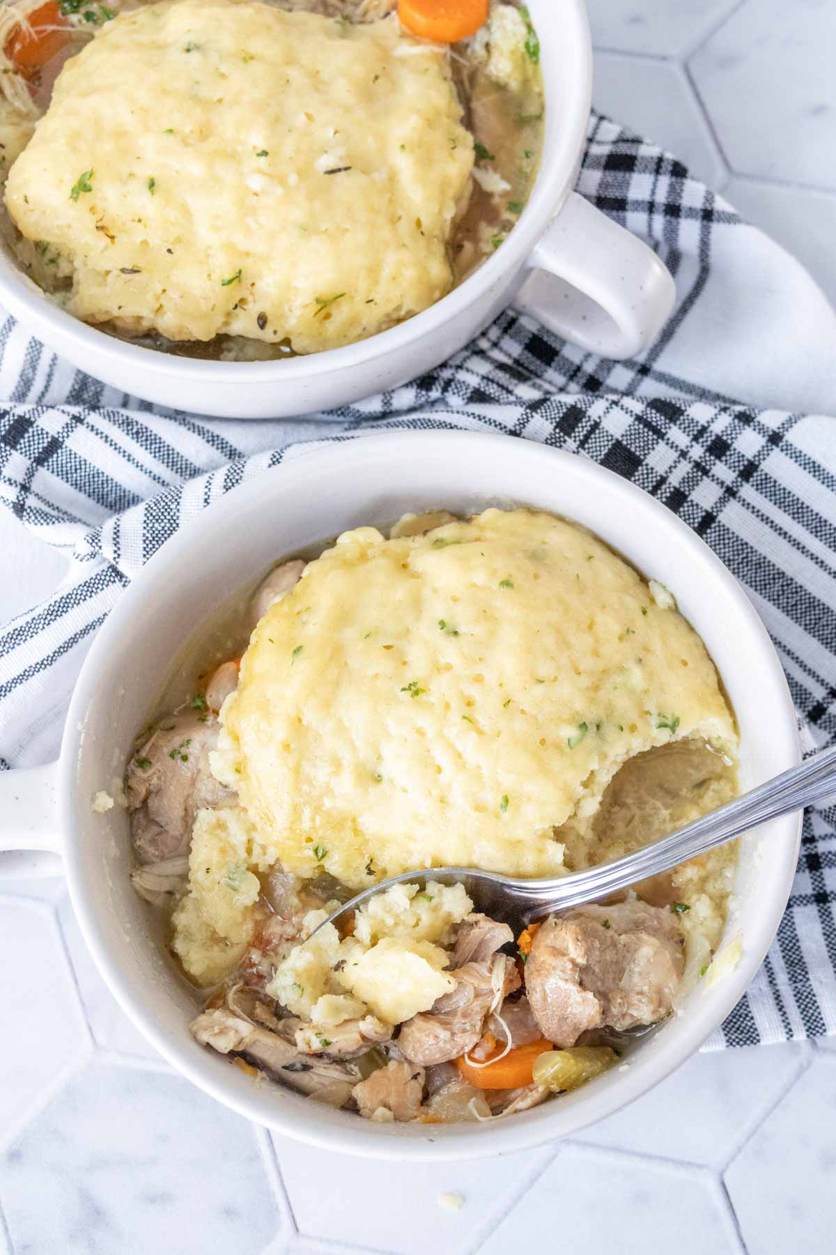 Bowl of chicken and dumplings with a spoon scooping some up.