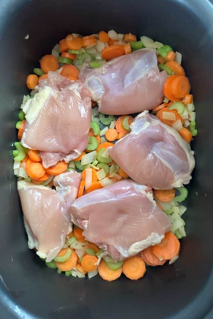 Chicken thighs and vegetables in a slow cooker.