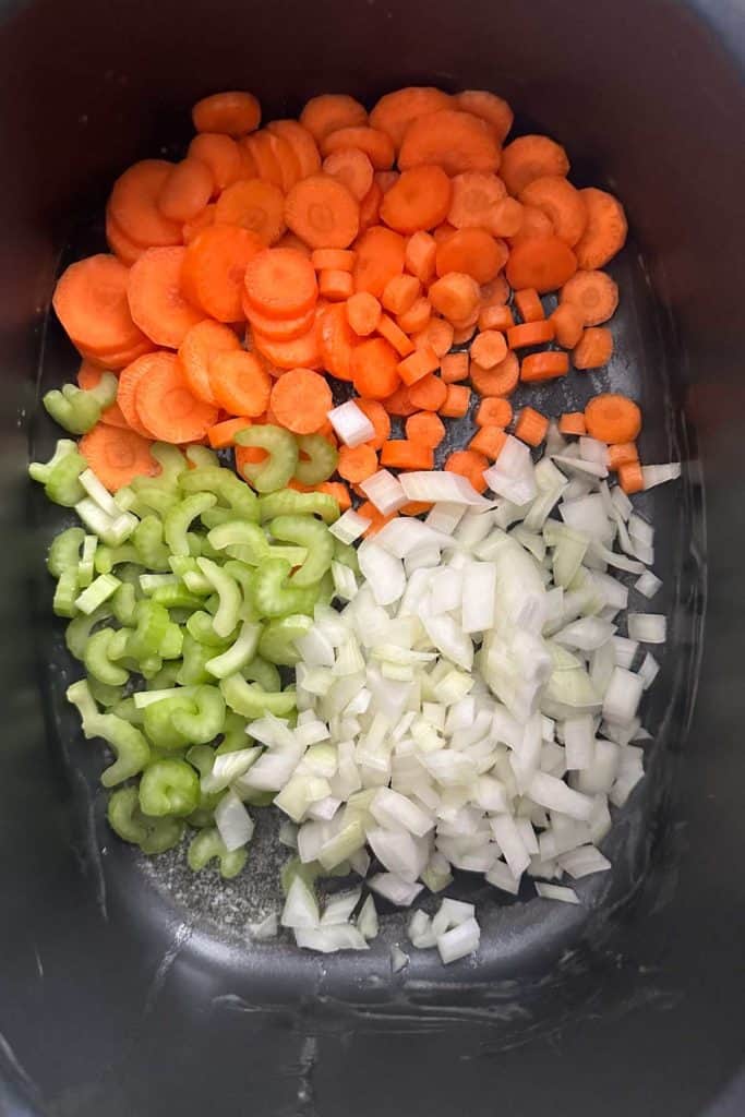 Carrots, onion, and celery being sauteed in a pot.