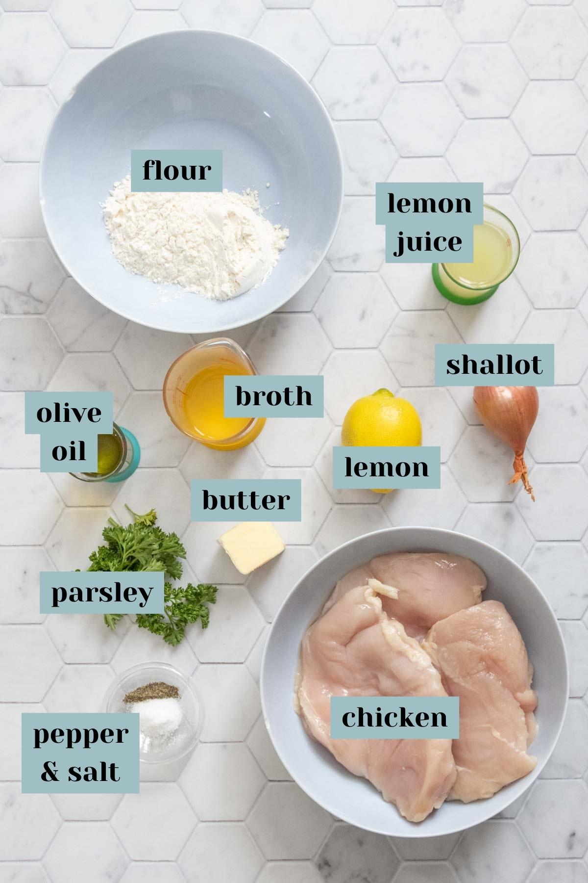 Ingredients for lemon chicken on a tile surface with labels.