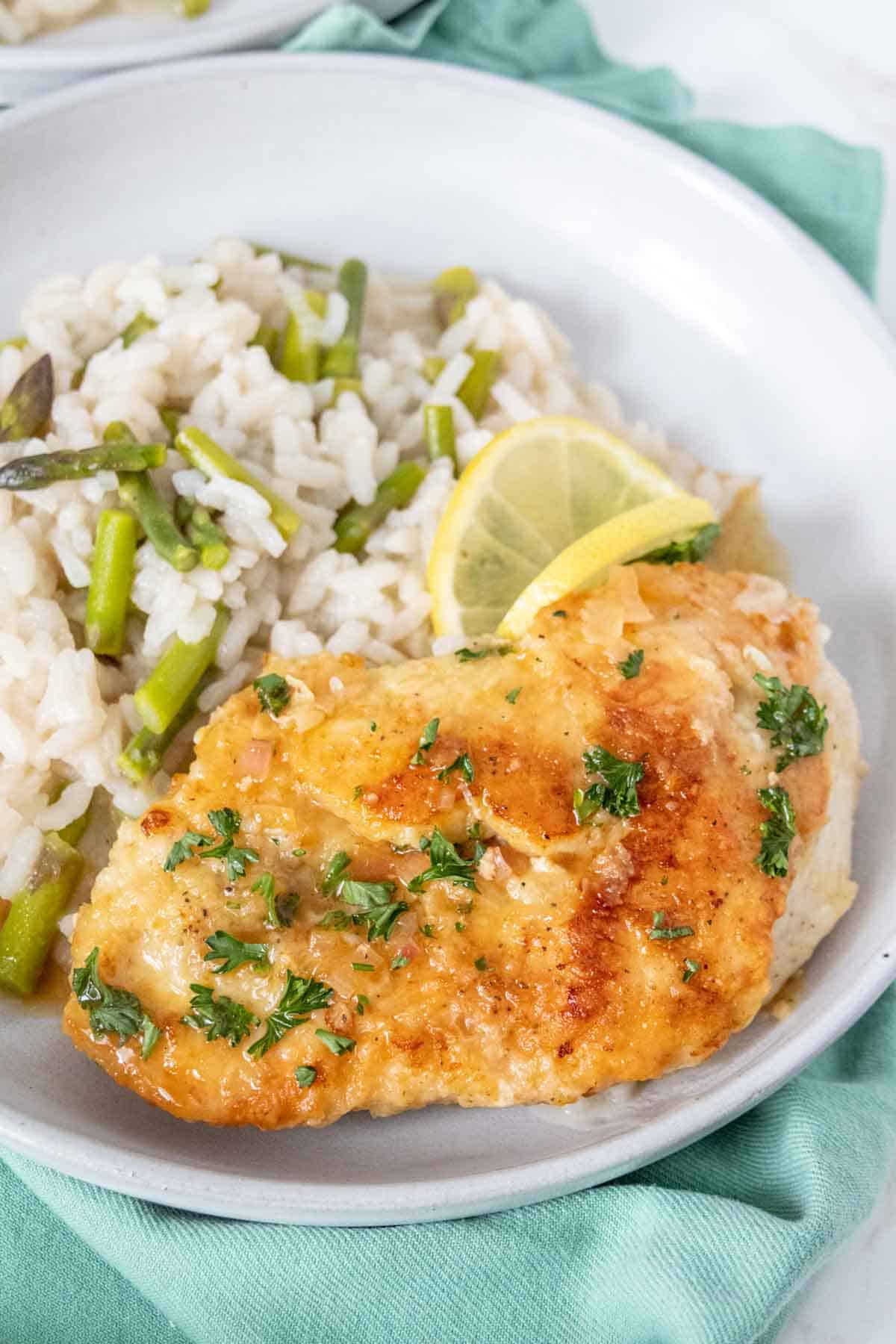 Lemon chicken on a plate next to risotto.