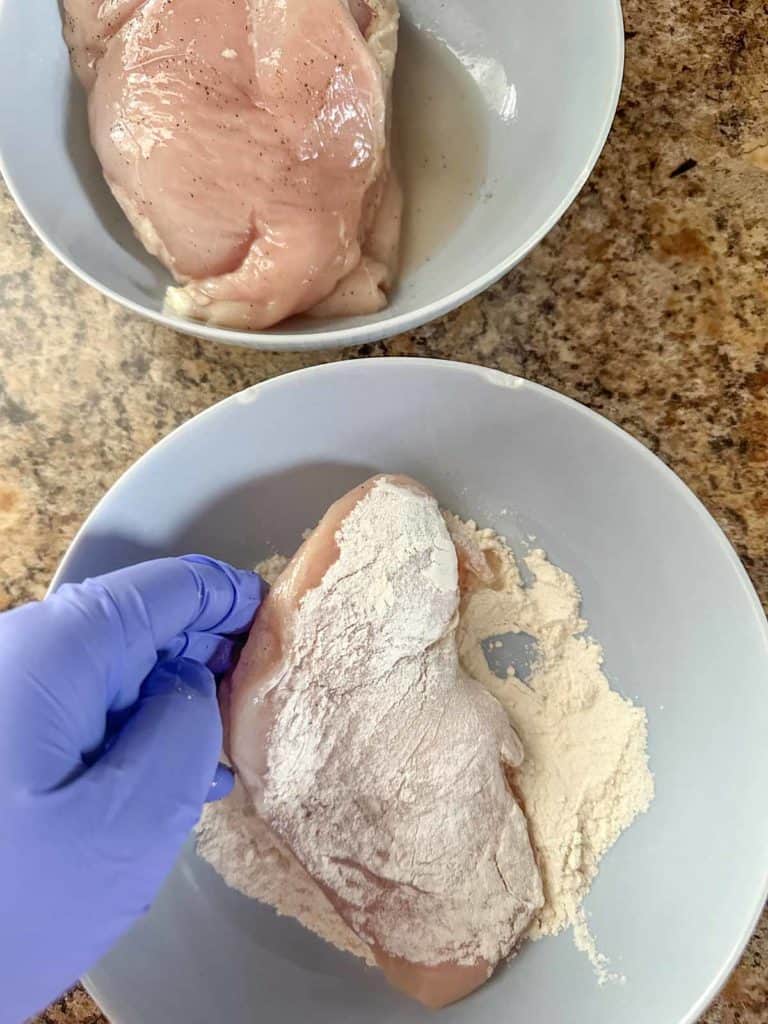 Dredging chicken breasts in flour.