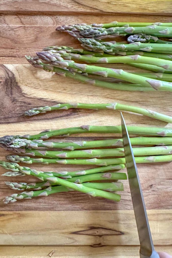 Cutting asparagus on cutting board.
