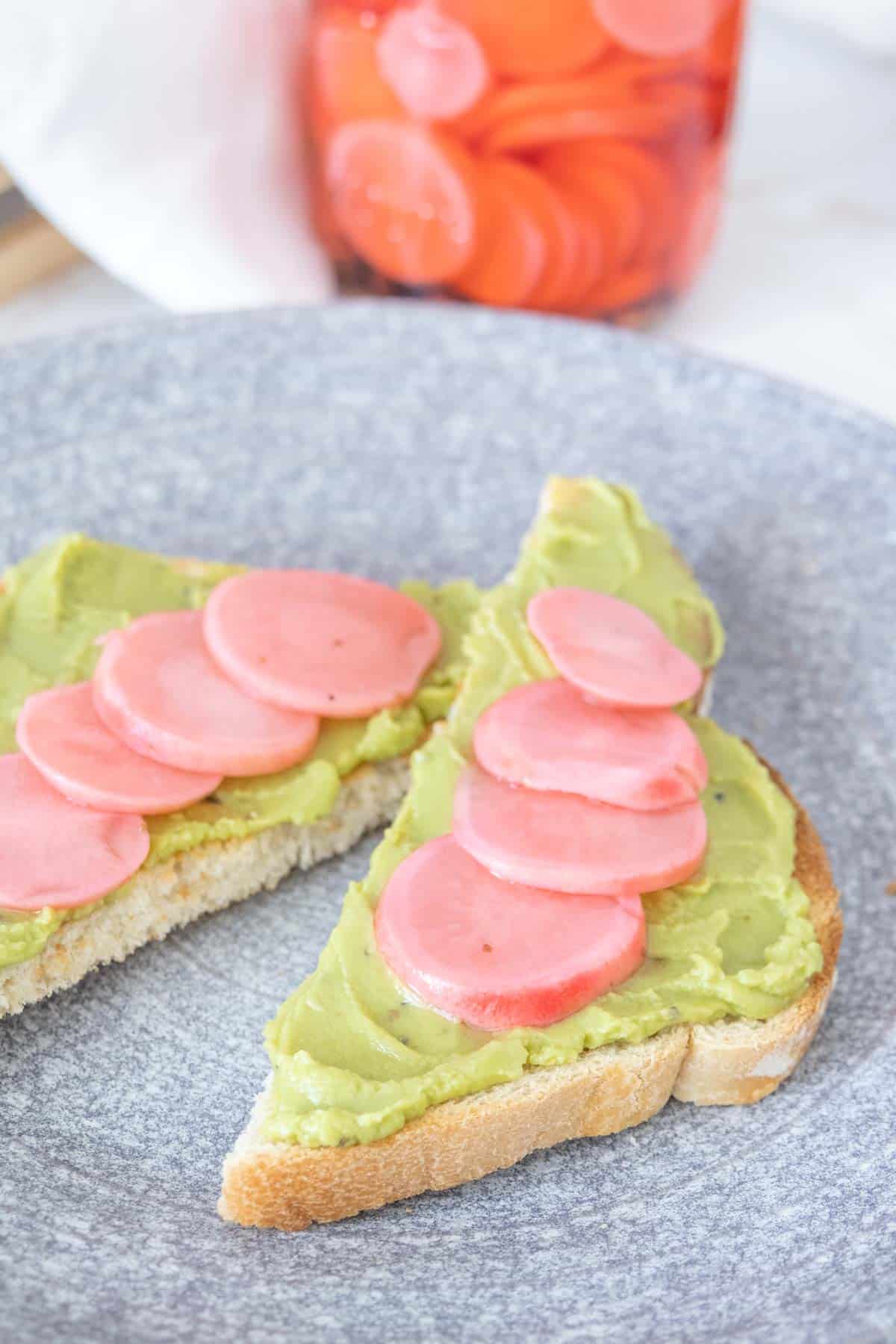 Pickled radishes on slices of avocado toast.