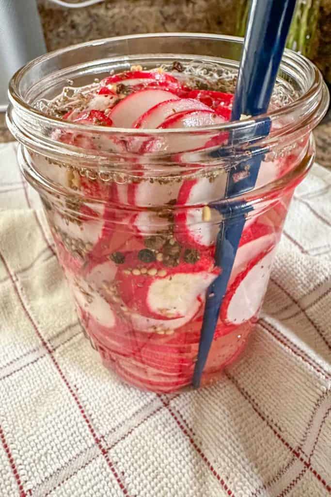 Using a chopstick to remove air bubbles in jar of radishes.