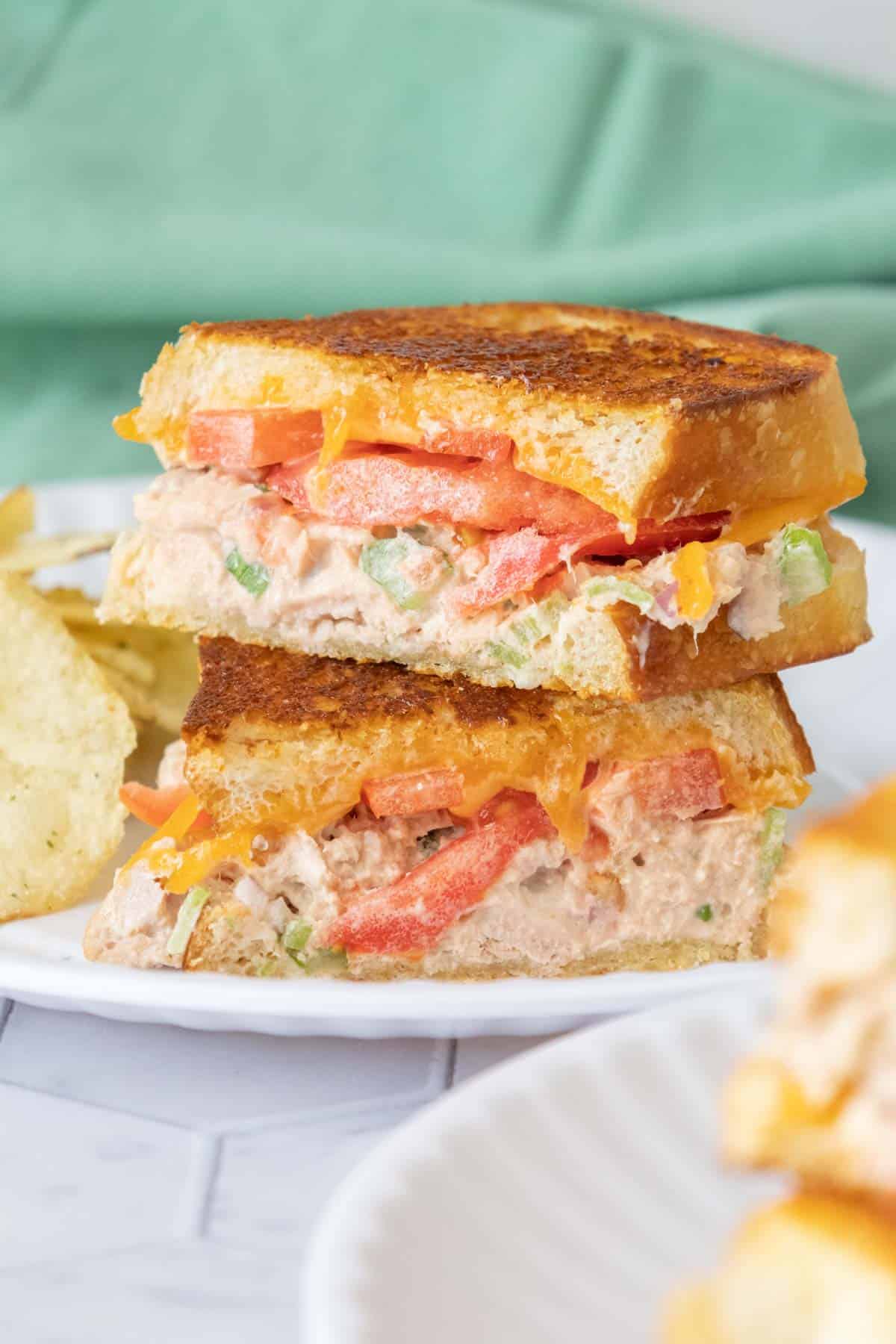 Stacked halves of tuna melt sandwiches on white plate.