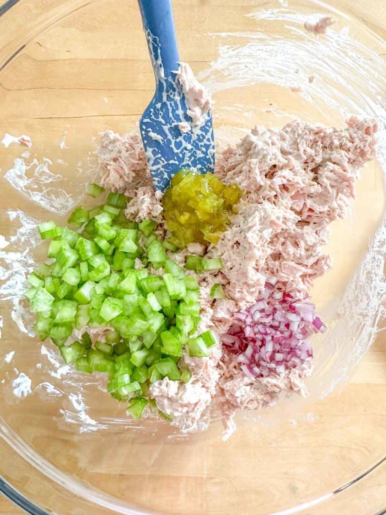 Ingredients for tuna salad in a glass mixing bowl.