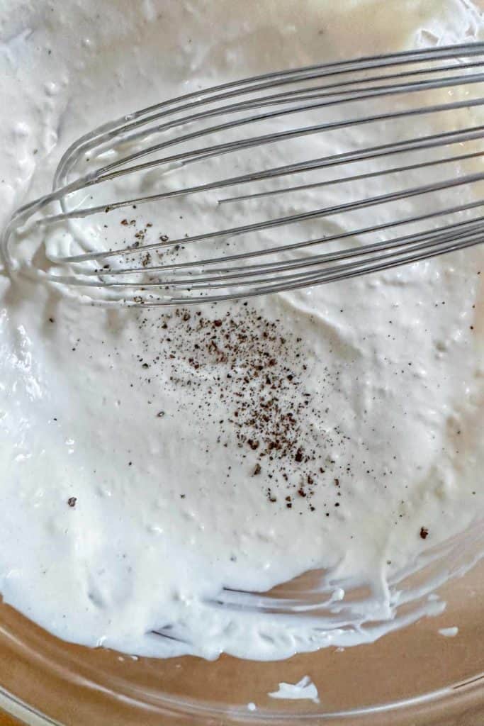 Cracked black pepper on Caesar salad dressing before whisking.